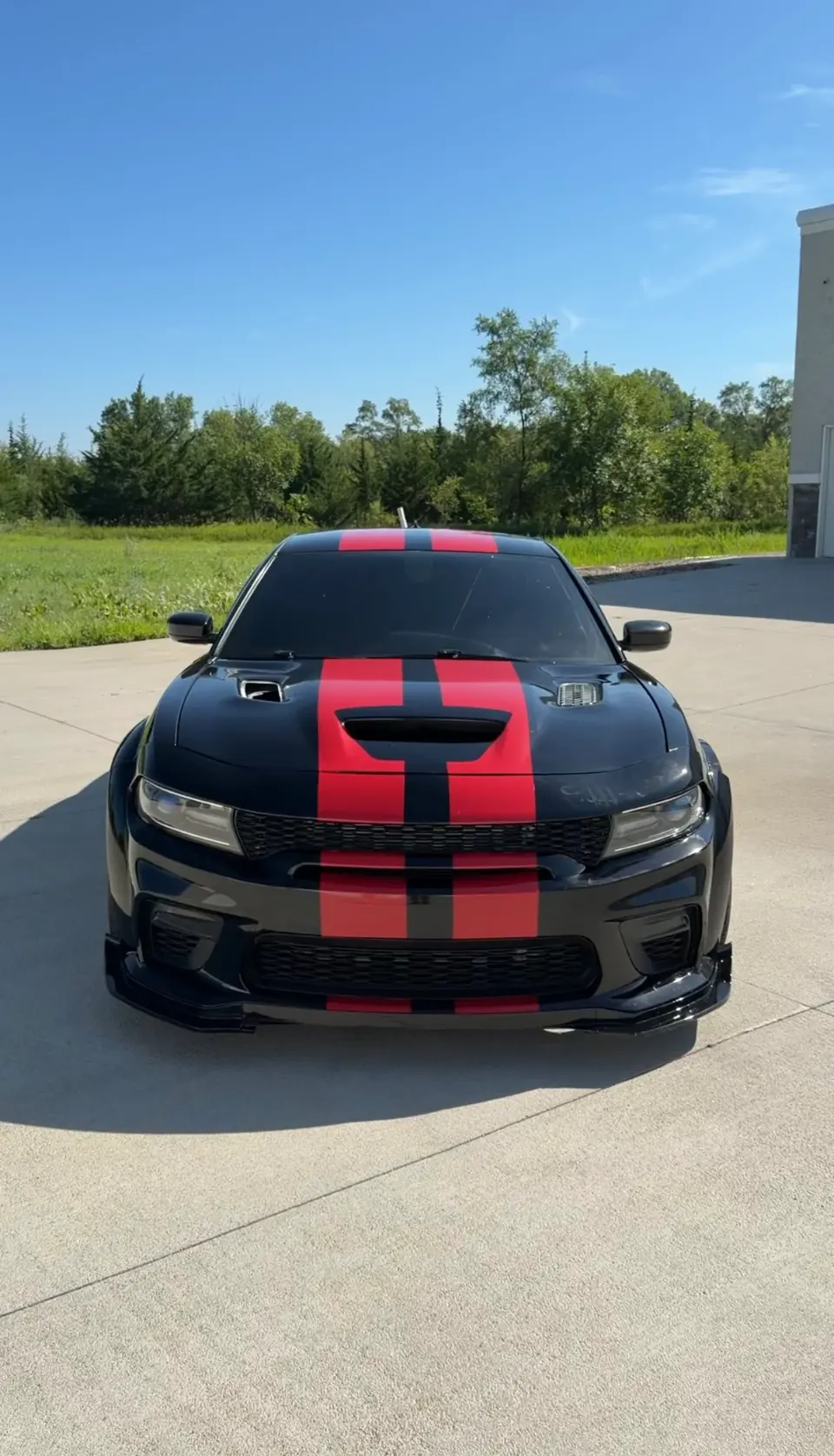 Black Dodge Charger with red racing stripes and tinted windows