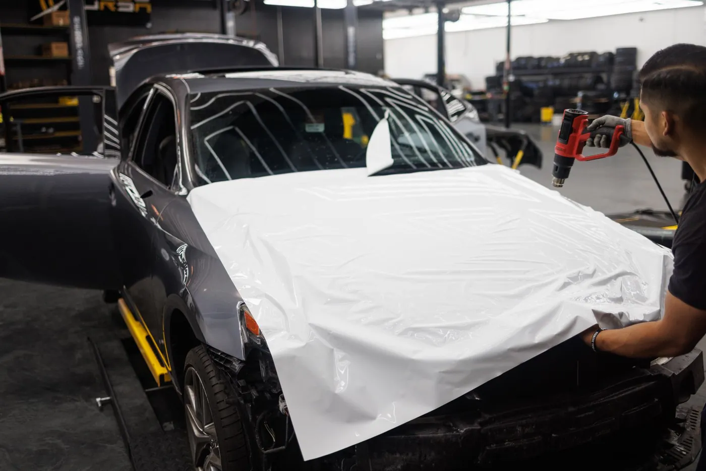 Professional applying vinyl wrap to a vehicle in a workshop